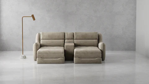 A modern two-seater sofa upholstered in a light taupe fabric, positioned in a minimalist room with a textured gray wall and a slim floor lamp on the left.