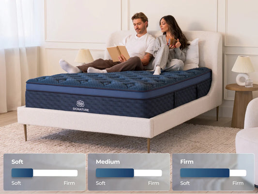 Couple sitting on a bed with a blue mattress, surrounded by home decor.